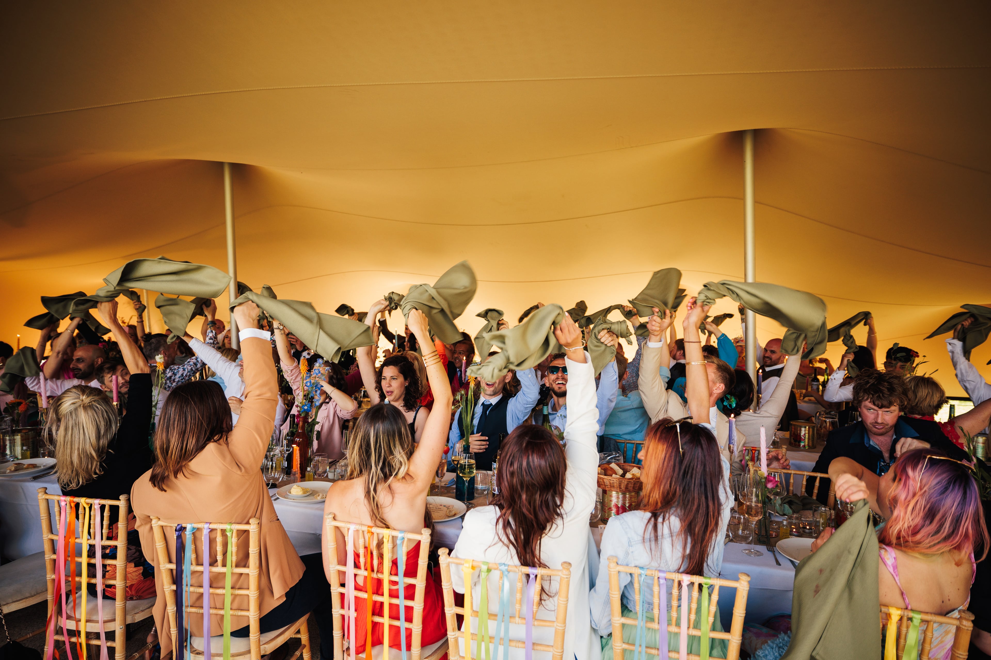 Guests celebrating under a glowing stretch tent canopy